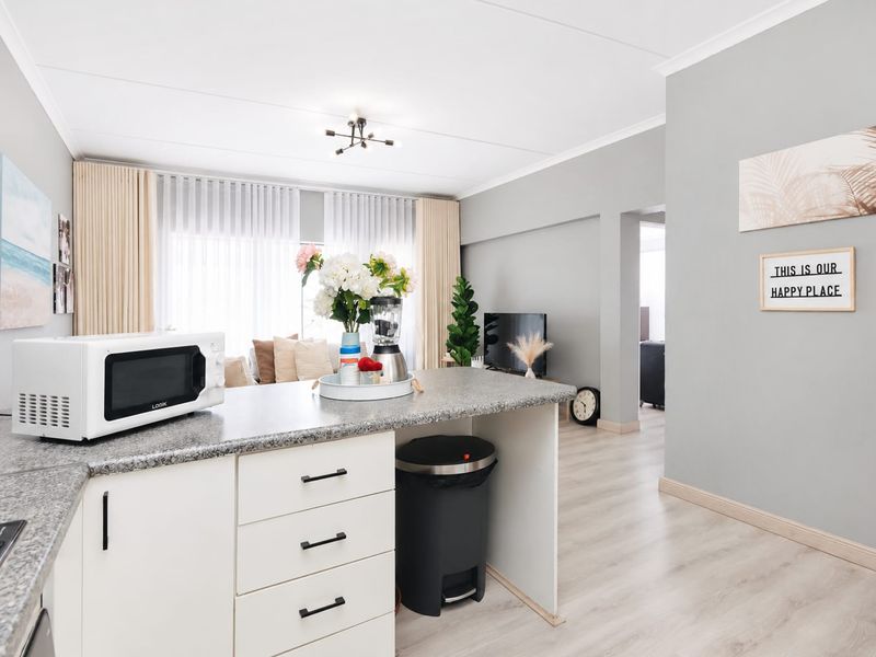 Bright open-plan living area featuring a modern kitchen with granite countertops and light laminate flooring, seamlessly flowing into the adjacent living space.