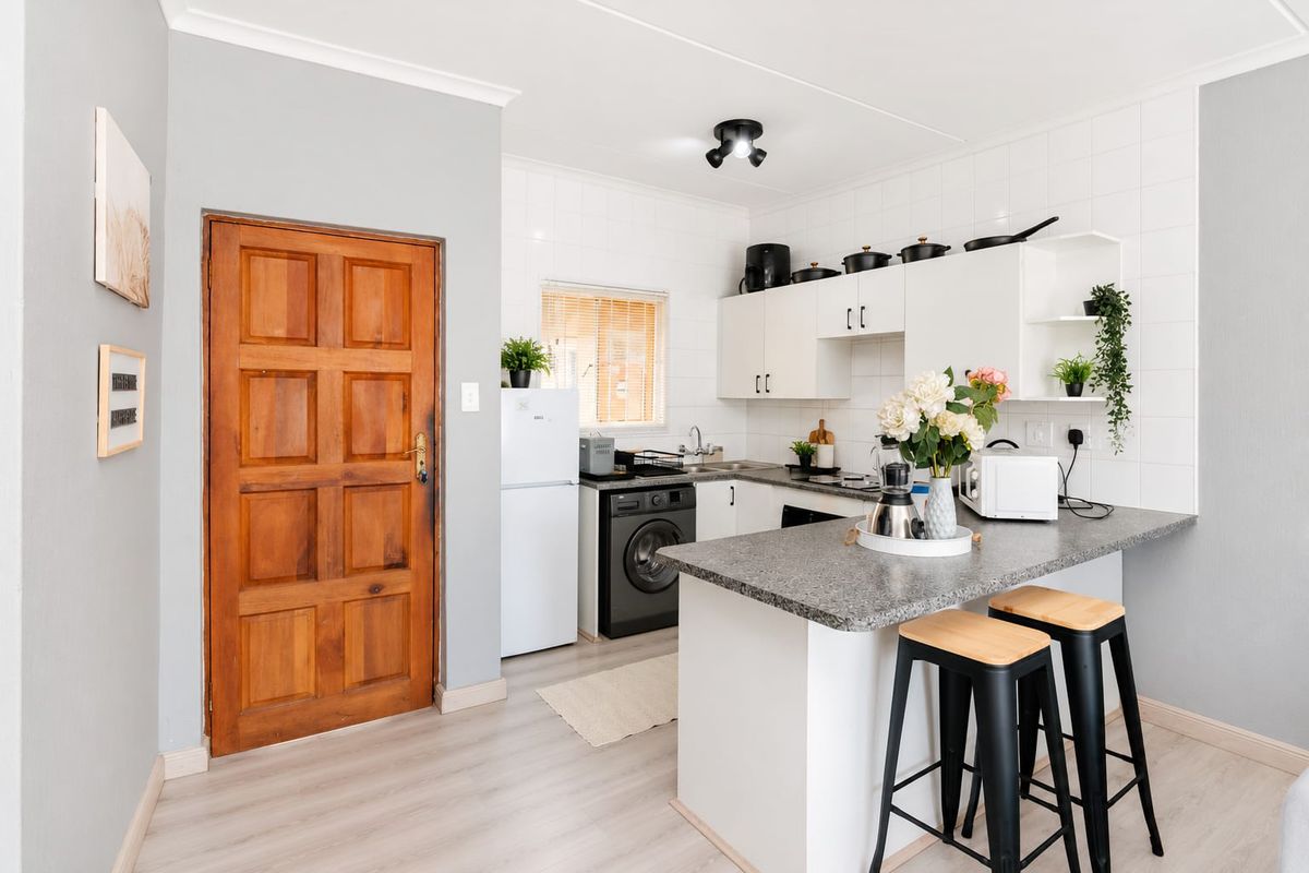 A functional kitchen featuring white cabinetry, laminate countertops, a breakfast bar, and tiled backsplash, providing a clean and practical cooking and dining space.
