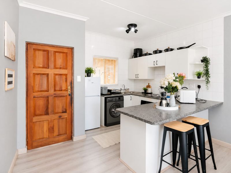 A functional kitchen featuring white cabinetry, laminate countertops, a breakfast bar, and tiled backsplash, providing a clean and practical cooking and dining space.