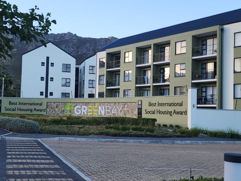 Exterior view of the Greenbay apartment complex, featuring modern multi-story architecture, private balconies, and landscaped grounds with a prominent entrance signage.