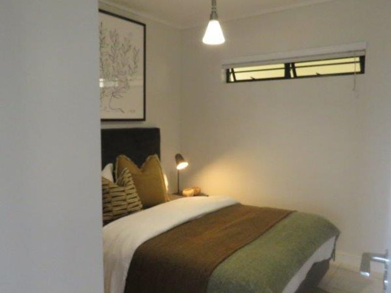 A cozy bedroom featuring tiled flooring, a horizontal window, and a modern pendant light fixture.
