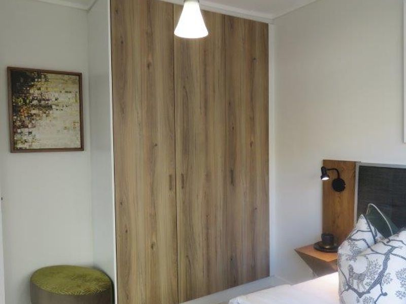 A well-maintained bedroom featuring a modern wood-finish built-in wardrobe and integrated wall-mounted lighting.