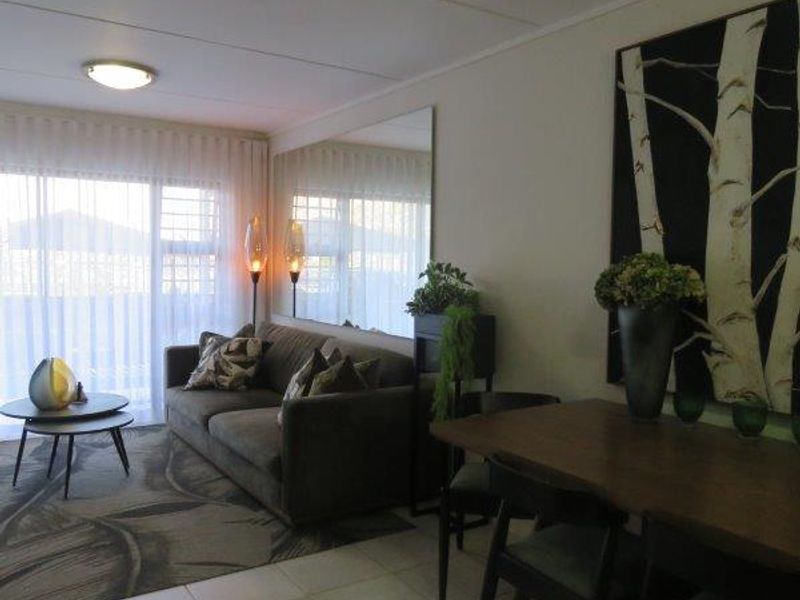 Open plan living and dining area featuring tiled flooring, a large wall-mounted mirror, and sliding glass doors providing access to the exterior.