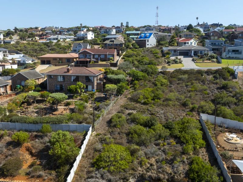 An aerial view of a vacant residential plot featuring natural vegetation and perimeter fencing, situated within an established suburban neighborhood.