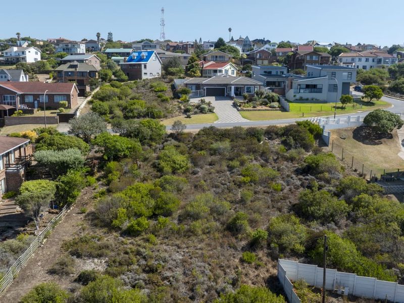 An aerial view of a vacant residential plot surrounded by established suburban housing and natural vegetation.