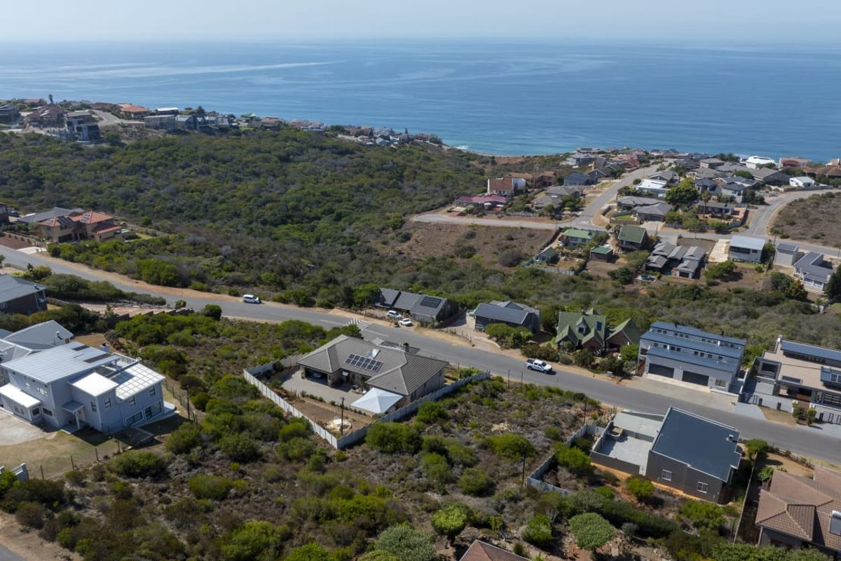 An aerial view of a residential coastal neighborhood featuring established homes, natural vegetation, and proximity to the ocean.