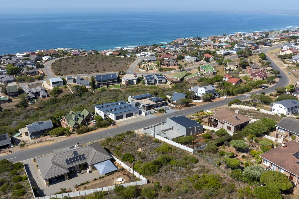 An elevated aerial view of a coastal residential neighborhood, showcasing the surrounding landscape, street layout, and proximity to the ocean.