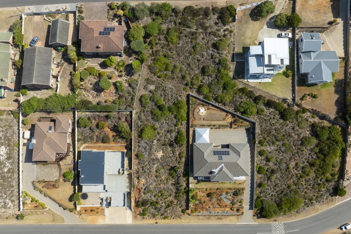 An aerial view of a vacant residential plot situated within an established neighborhood, showing surrounding properties and site boundaries.