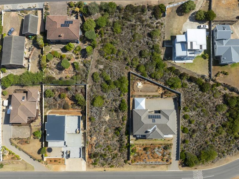 An aerial view of a vacant residential plot situated within an established neighborhood, showing surrounding properties and site boundaries.