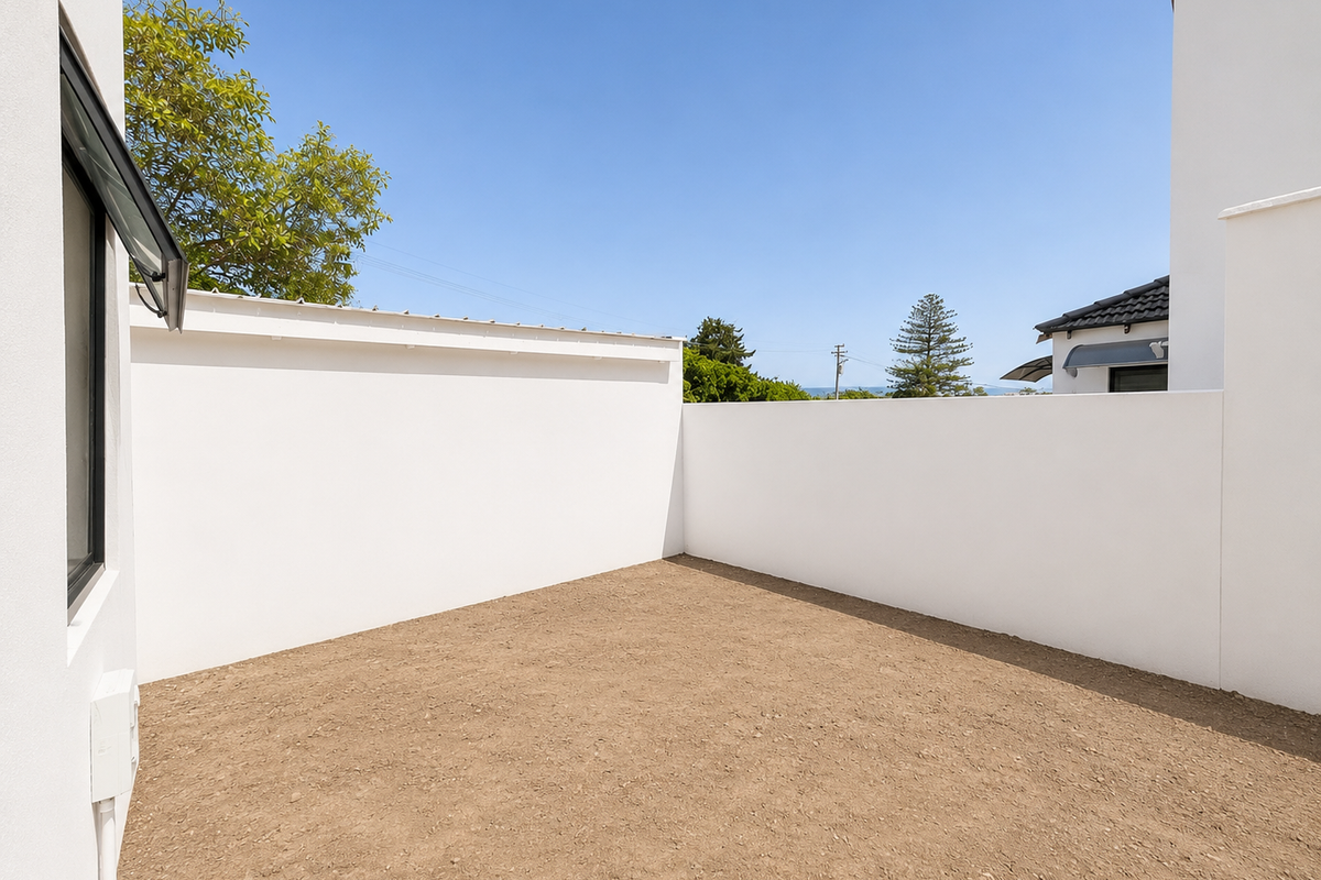 A private, enclosed rear courtyard area featuring high boundary walls and an unlandscaped ground surface, ready for custom garden design.