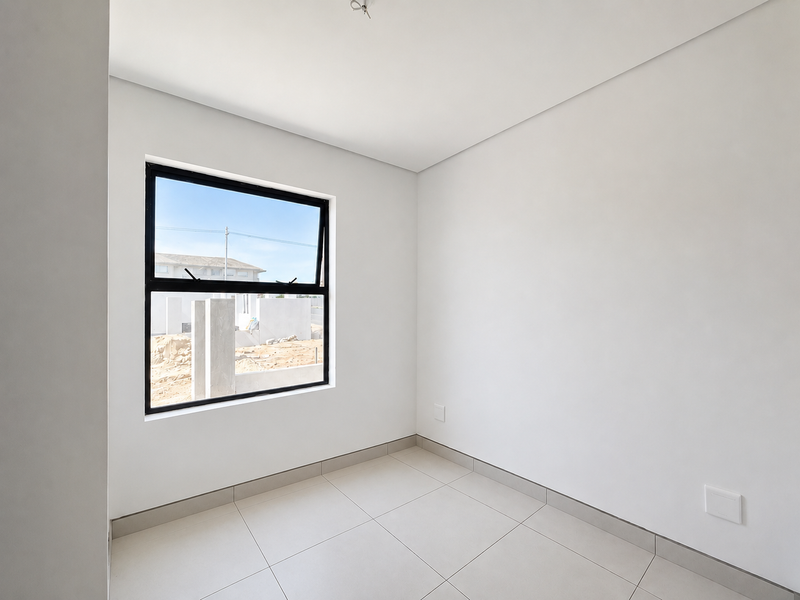 A bright, empty bedroom featuring neutral tiled flooring, clean white walls, and a modern black aluminium window frame.