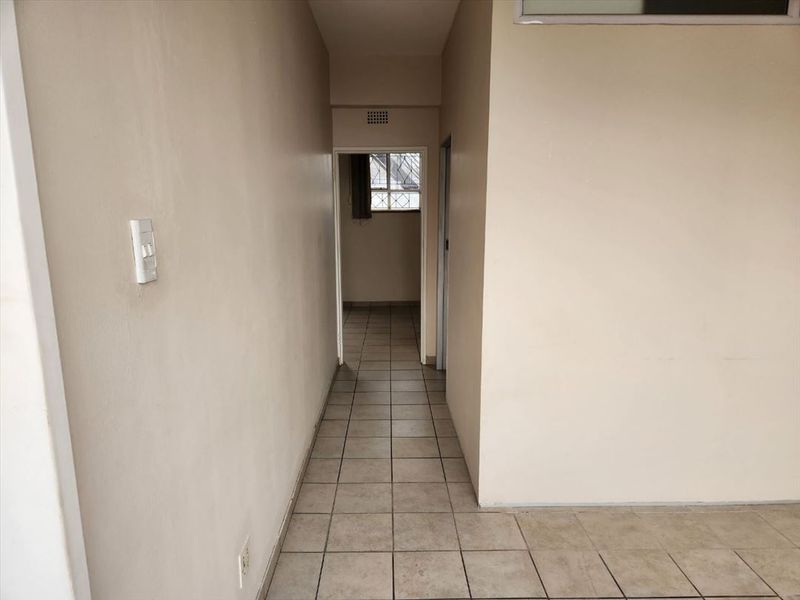 A functional, empty hallway featuring neutral wall paint and tiled flooring, providing access to adjacent rooms within the apartment.