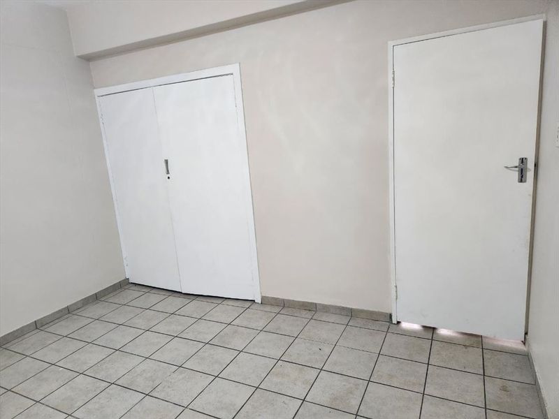 An empty bedroom featuring tiled flooring and built-in cupboard storage, providing a neutral blank canvas ready for personalization.