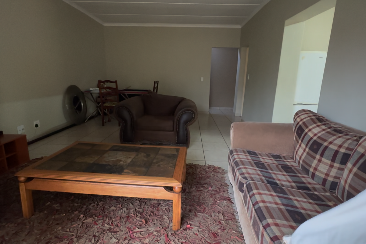 A spacious living room featuring neutral wall tones, tiled flooring, and a coved ceiling, providing a functional and open layout.
