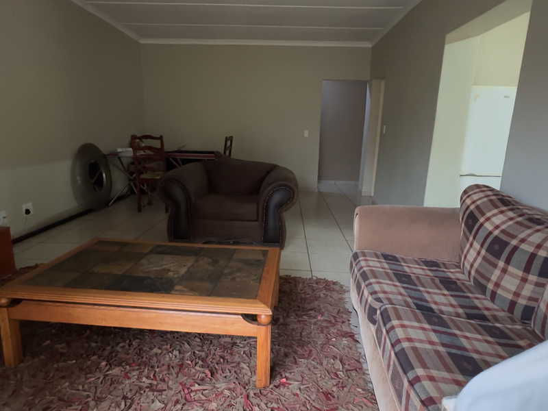 A spacious living room featuring neutral wall tones, tiled flooring, and a coved ceiling, providing a functional and open layout.