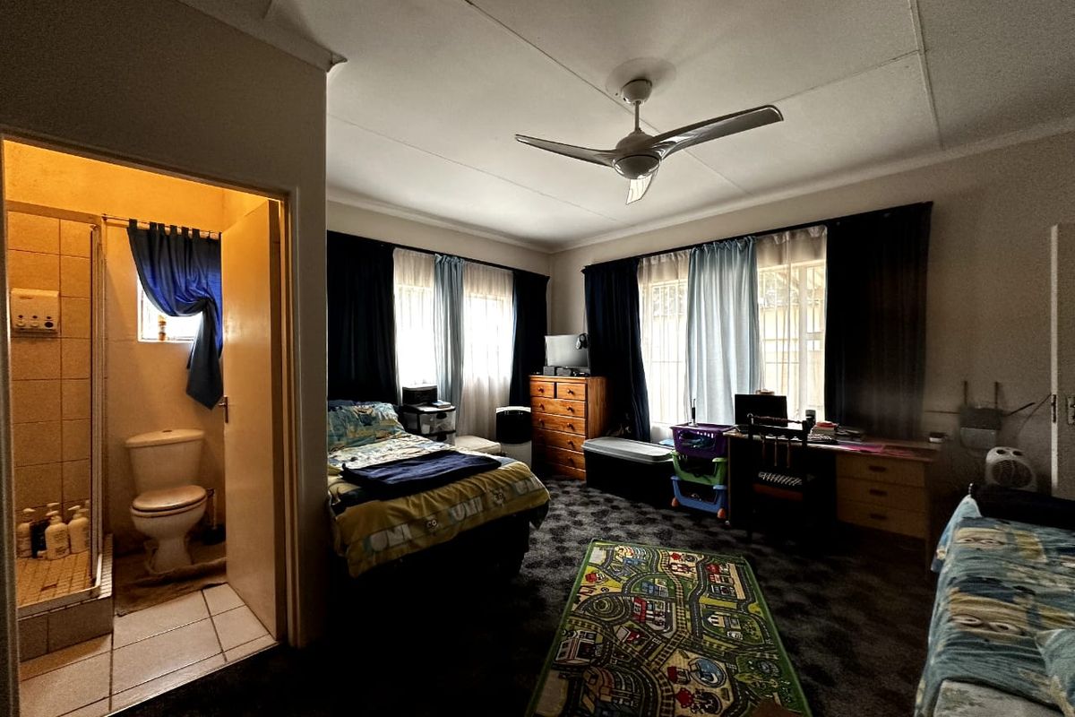 A bedroom featuring an en-suite bathroom with a shower and toilet, equipped with a ceiling fan and carpeted flooring.