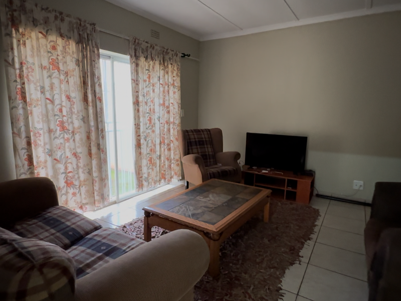 A living room featuring tiled flooring and a sliding glass door providing access to the exterior.