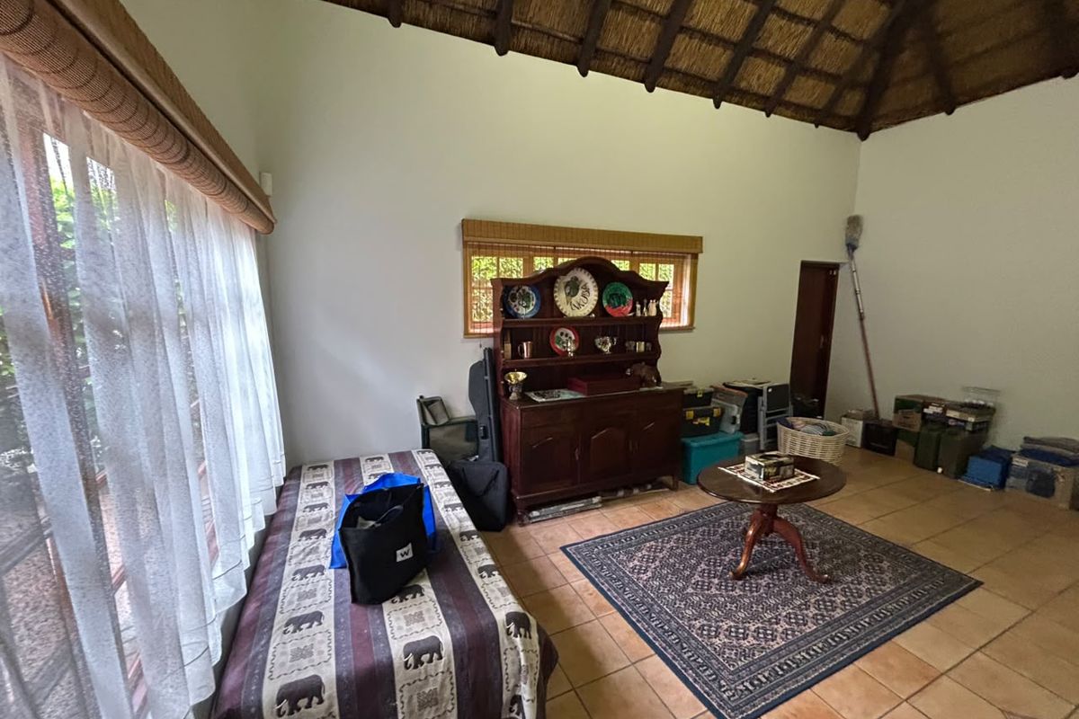 A living area featuring a high vaulted thatched ceiling with exposed timber rafters and tiled flooring, offering a rustic and spacious atmosphere.