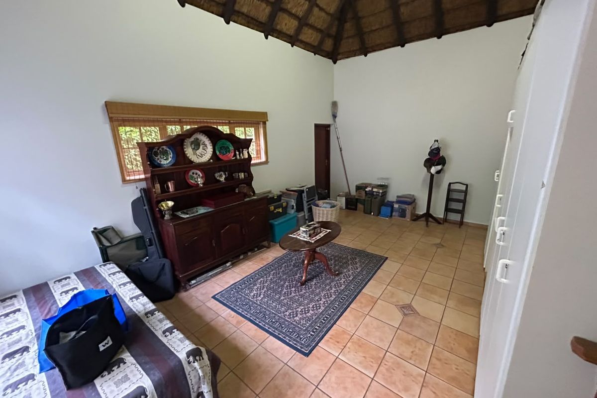 Spacious bedroom featuring a high vaulted thatched ceiling, tiled flooring, and built-in storage cupboards.
