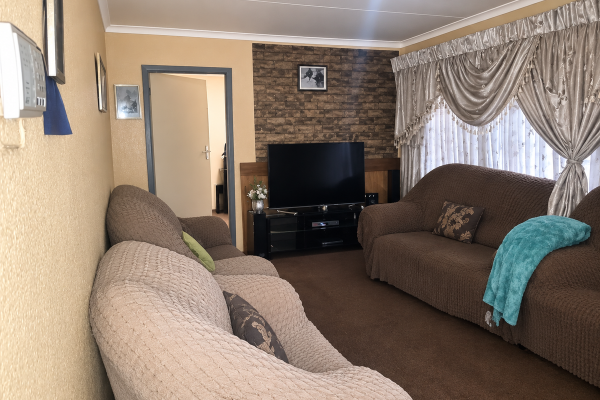 A comfortable living room featuring a brick-effect accent wall, neutral wall tones, and carpeted flooring, providing a cozy space for relaxation.
