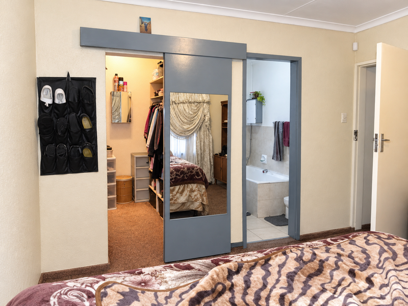 Bedroom featuring a sliding barn door providing access to a walk-in closet and an en-suite bathroom with a built-in bathtub.