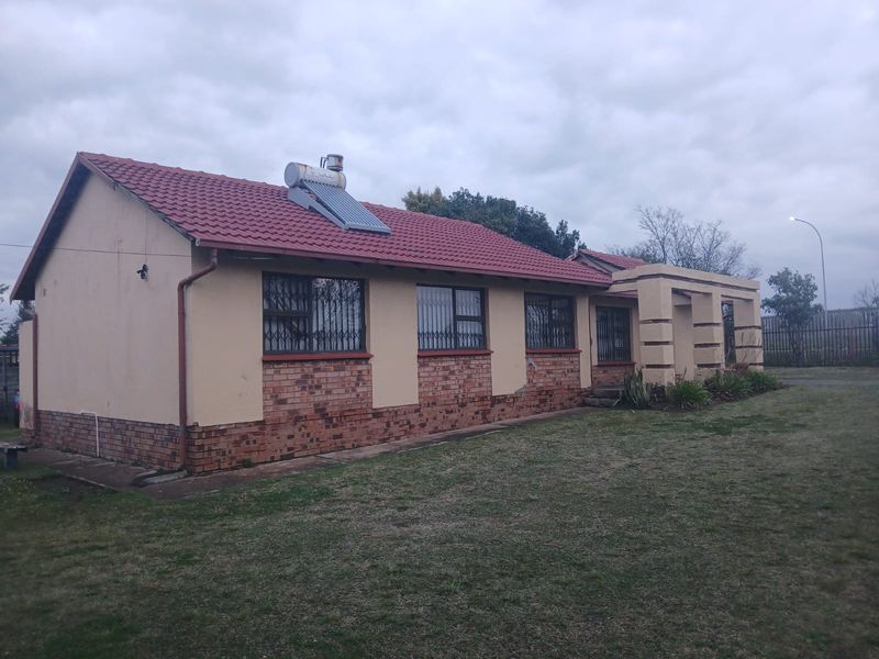 A single-story residential house featuring a tiled roof, solar water heating system, and a combination of brick and plastered exterior walls.