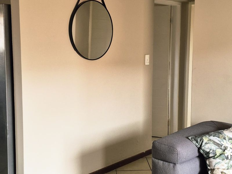 A well-maintained living area featuring neutral wall tones, tiled flooring, and coved ceiling details, providing a clean and functional space.