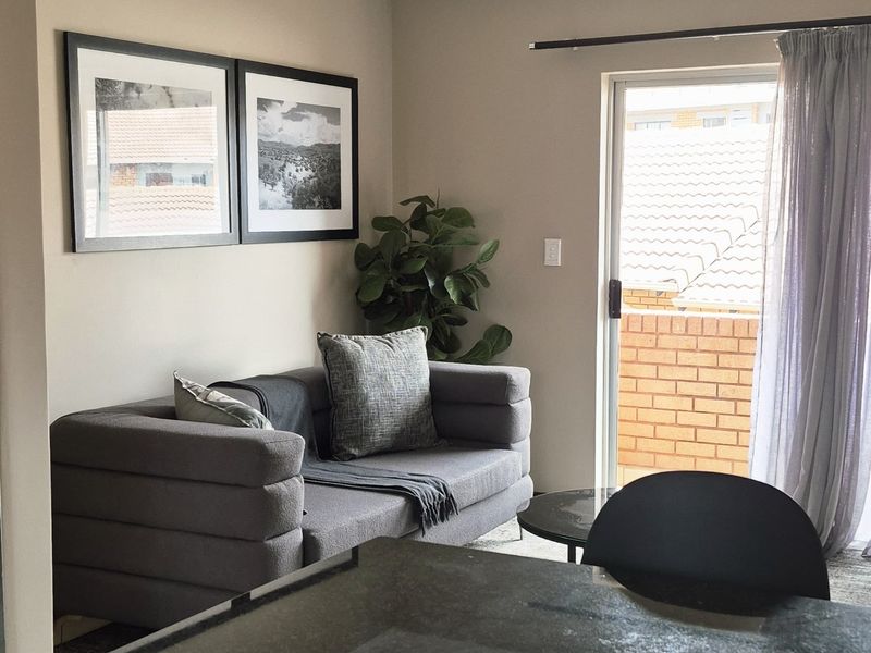 Open plan living area featuring a modern kitchen island with stone countertop and direct access to a private balcony through sliding glass doors.