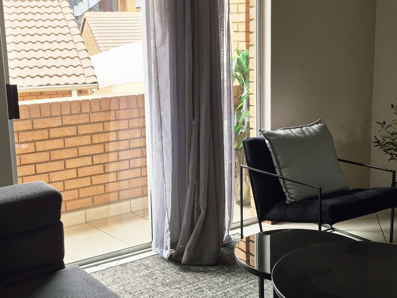 A comfortable living room featuring a large sliding glass door that opens onto a private balcony with brick detailing.