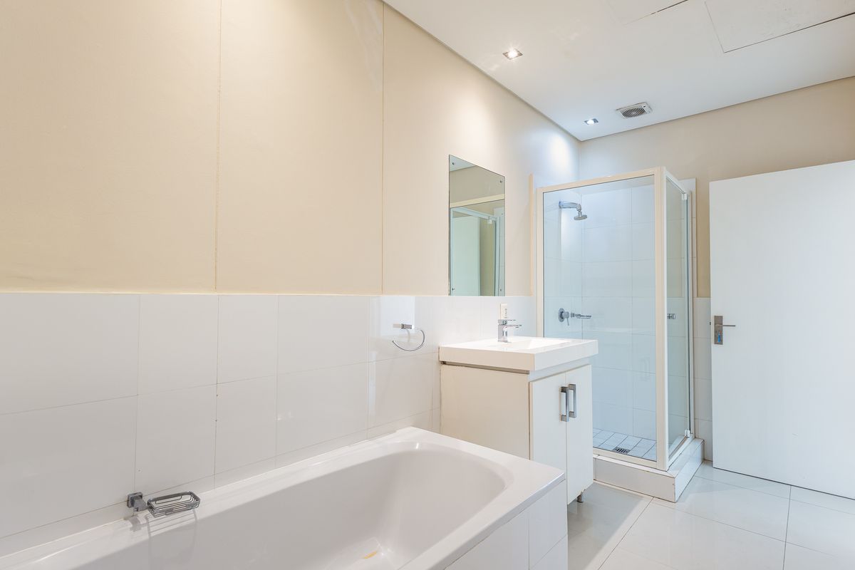 A clean, modern bathroom featuring a built-in bathtub, a separate shower enclosure, and a vanity unit with a basin.