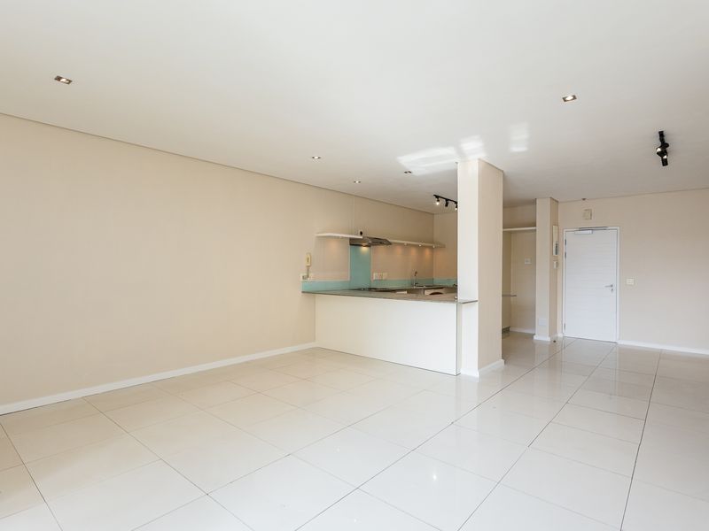 Spacious open-plan living area featuring tiled floors, recessed lighting, and a functional kitchen with a breakfast counter and built-in appliances.