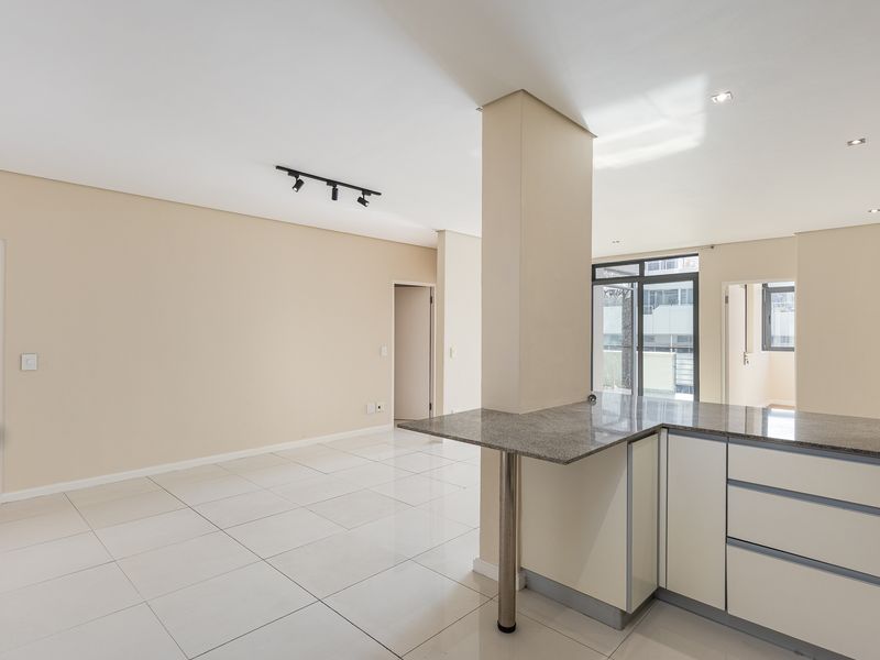 Spacious open-plan living area featuring tiled floors, modern kitchen cabinetry with granite countertops, and ample natural light through sliding glass doors.