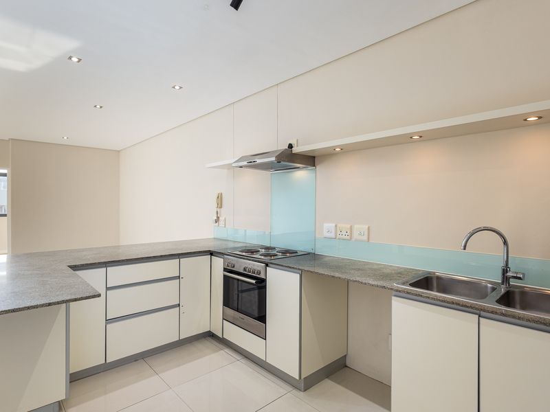 Modern kitchen featuring granite countertops, built-in oven, electric hob, extractor fan, and a stainless steel double sink with glass splashback.