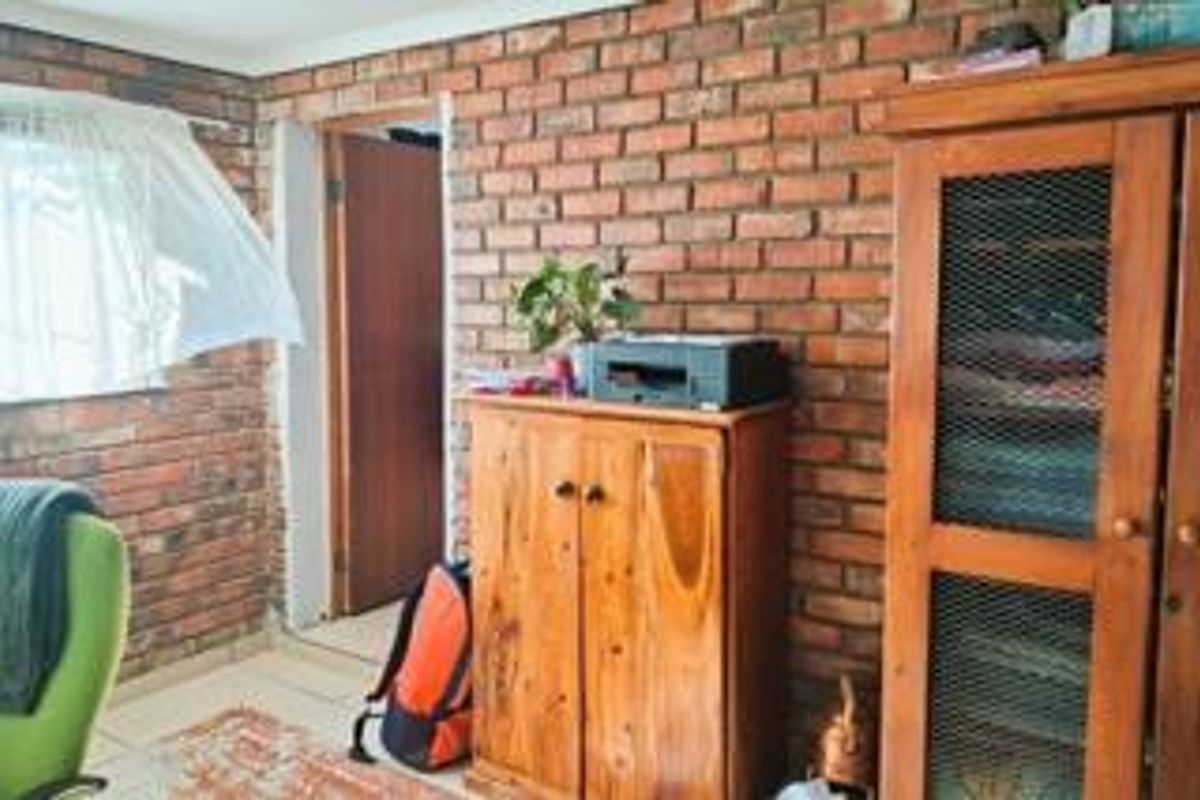 A bedroom featuring exposed brick walls and tiled flooring, offering a rustic aesthetic with potential for modern updates.