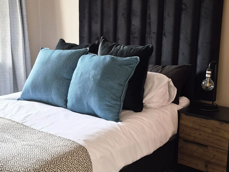 A well-maintained bedroom featuring neutral wall tones, tiled flooring, and integrated curtain tracks, providing a clean and comfortable living space.