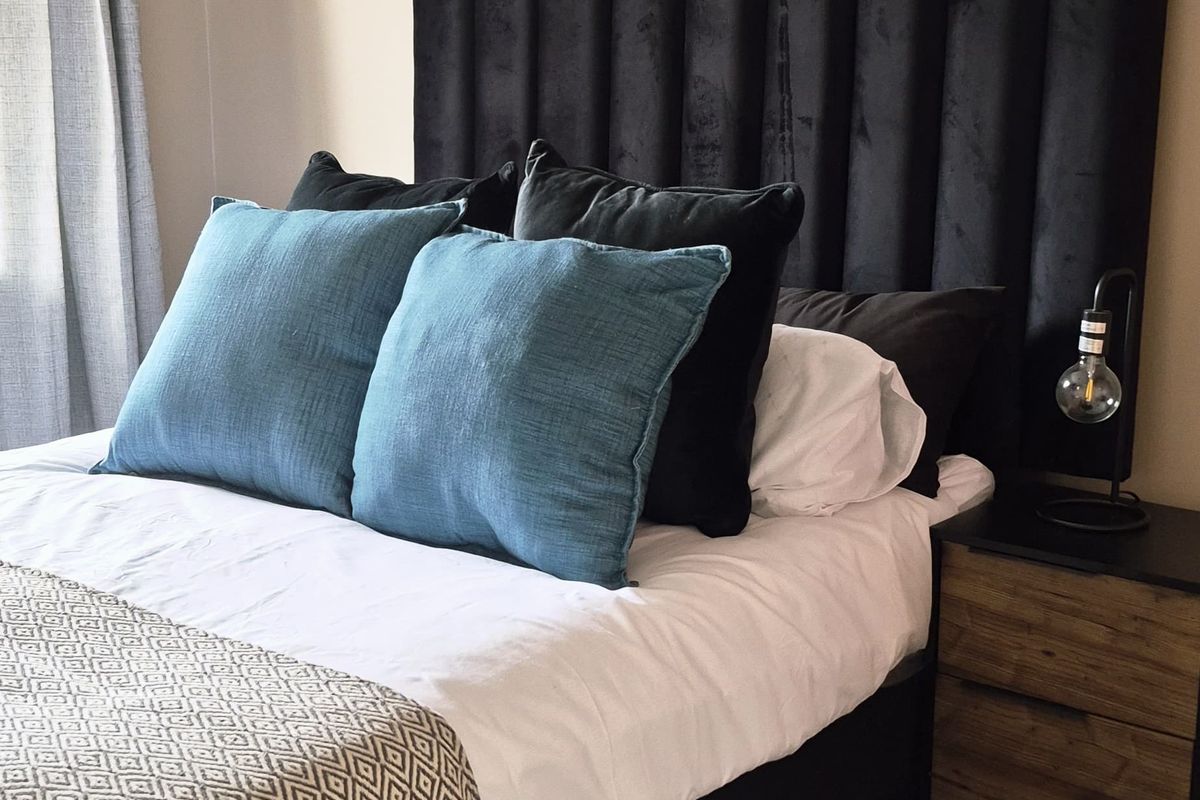 A well-maintained bedroom featuring neutral wall tones, tiled flooring, and integrated curtain tracks, providing a clean and comfortable living space.