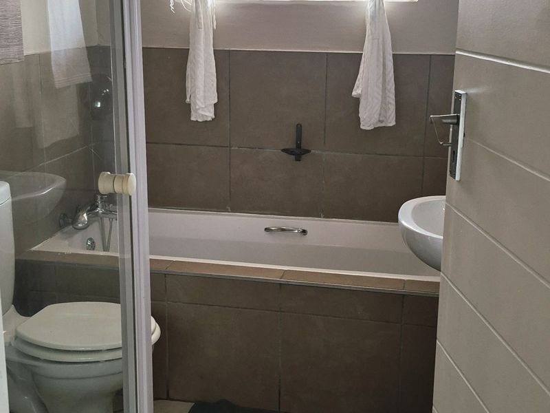 A functional bathroom featuring a bathtub, separate shower enclosure, pedestal basin, and tiled finishes throughout.
