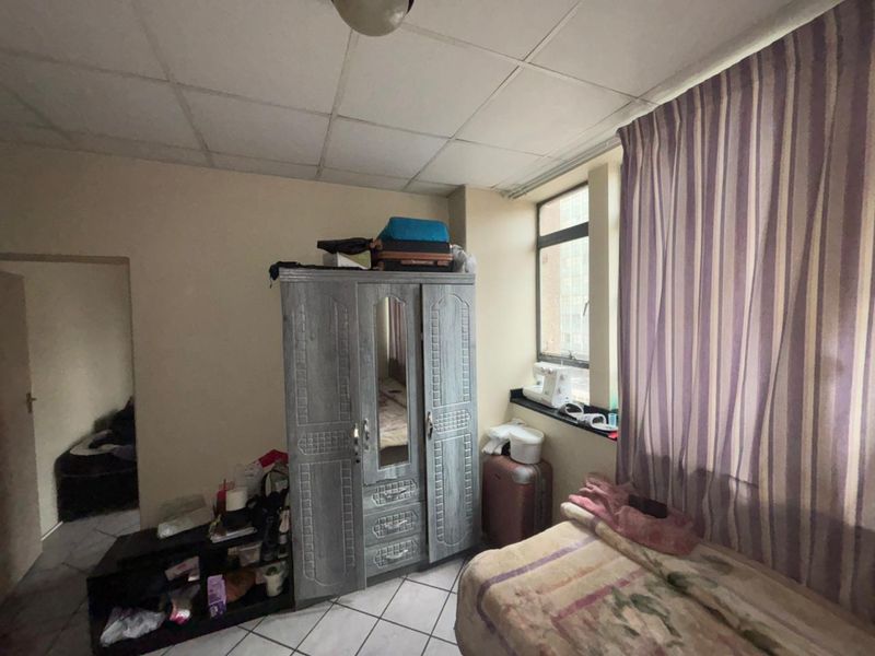 A bedroom featuring tiled flooring and a drop ceiling, requiring cosmetic updates to improve the overall condition and appeal of the space.