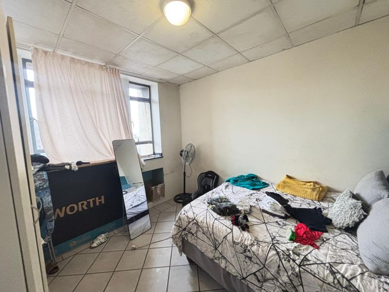 A bedroom featuring tiled flooring and a drop ceiling, requiring cosmetic updates to improve the overall condition and aesthetic appeal.