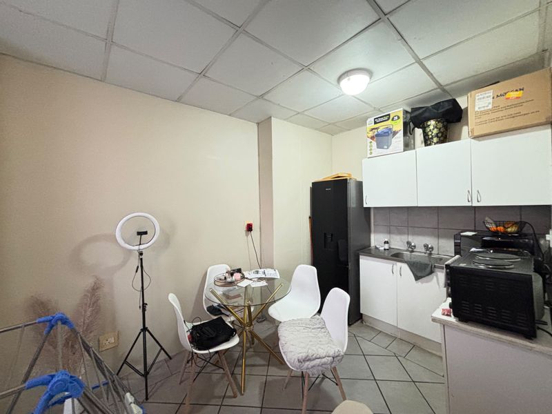 Compact kitchen area featuring built-in cabinetry, a stainless steel sink, and tiled flooring, requiring cosmetic updates to improve the overall aesthetic.