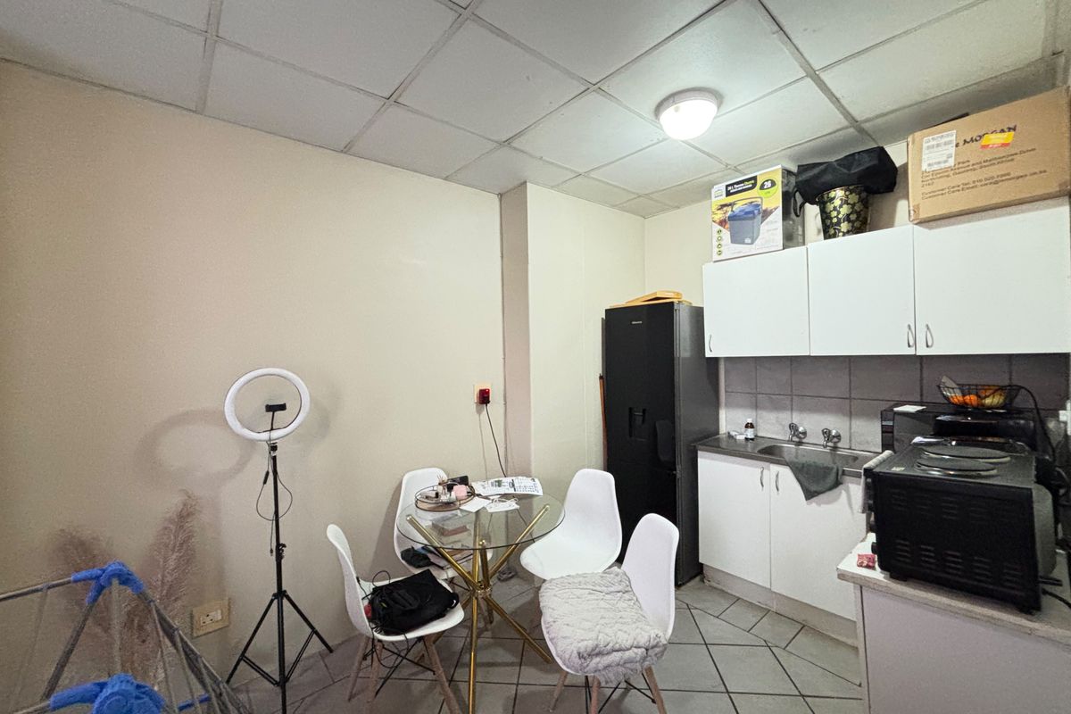 Compact kitchen area featuring built-in cabinetry, a stainless steel sink, and tiled flooring, requiring cosmetic updates to improve the overall aesthetic.