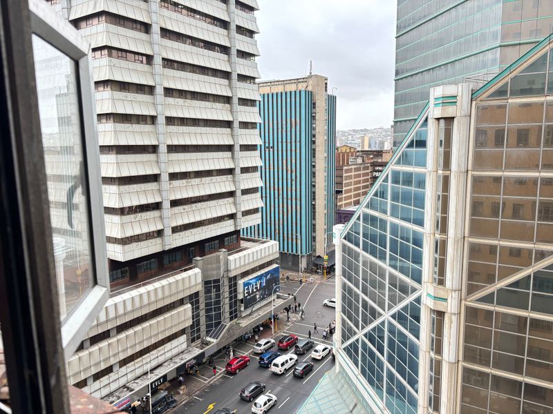 An elevated urban view looking out over a busy city street intersection surrounded by high-rise commercial and office buildings.