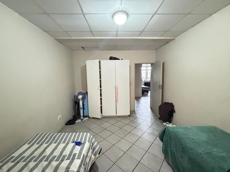 A bedroom featuring tiled flooring and a drop ceiling, requiring cosmetic updates to improve the overall aesthetic and finish.