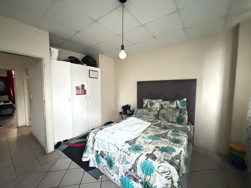 A bedroom featuring tiled flooring, a drop ceiling, and a built-in wardrobe, offering a functional space with potential for cosmetic updates.