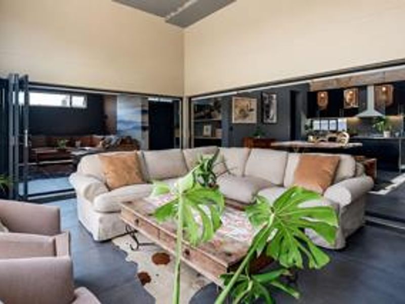 Spacious open-plan living area featuring high ceilings, large bi-fold doors, and a modern kitchen with integrated cabinetry and sleek finishes.