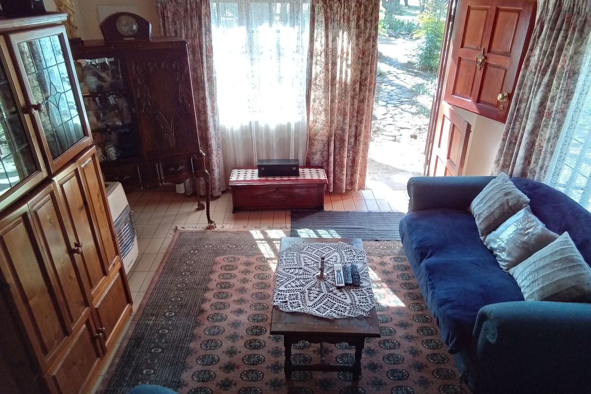A living room featuring tiled flooring, a gas heater, and direct access to the outdoor garden area through a timber door.