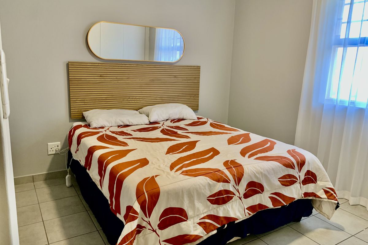 A well-maintained bedroom featuring neutral wall tones, tiled flooring, and a window with natural light, providing a clean and functional living space.