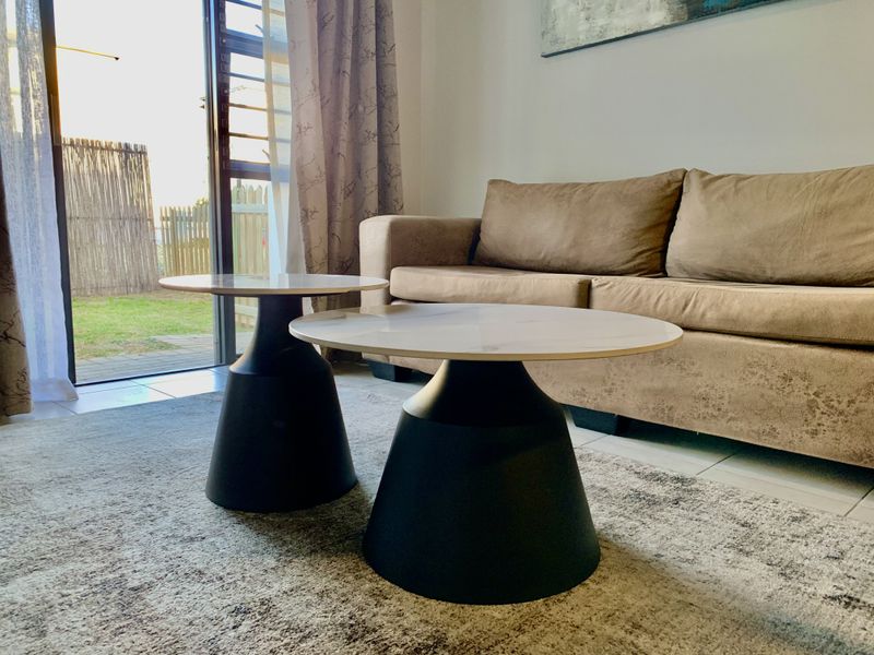 A bright living room featuring tiled flooring and a large sliding glass door providing direct access to the outdoor area.