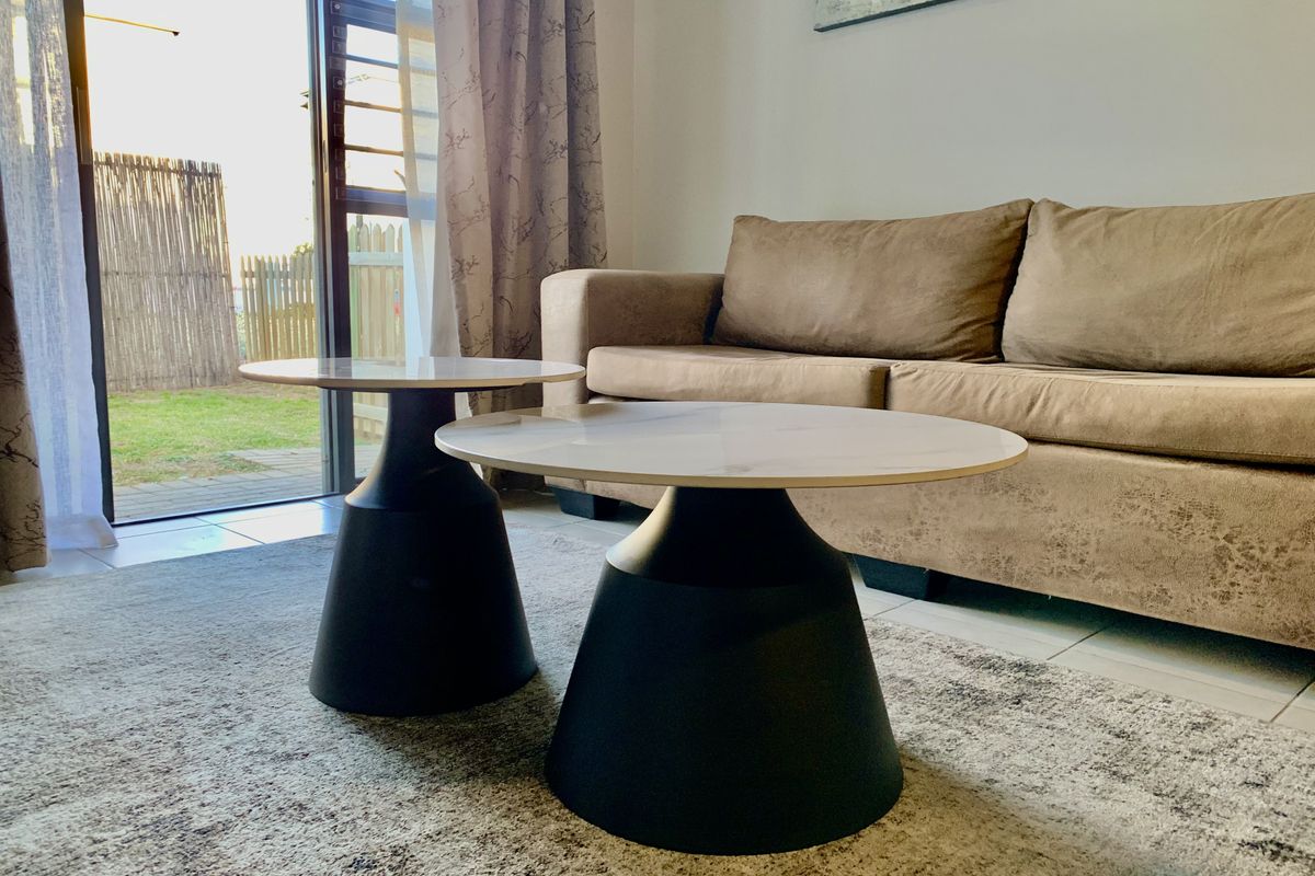 A bright living room featuring tiled flooring and a large sliding glass door providing direct access to the outdoor area.