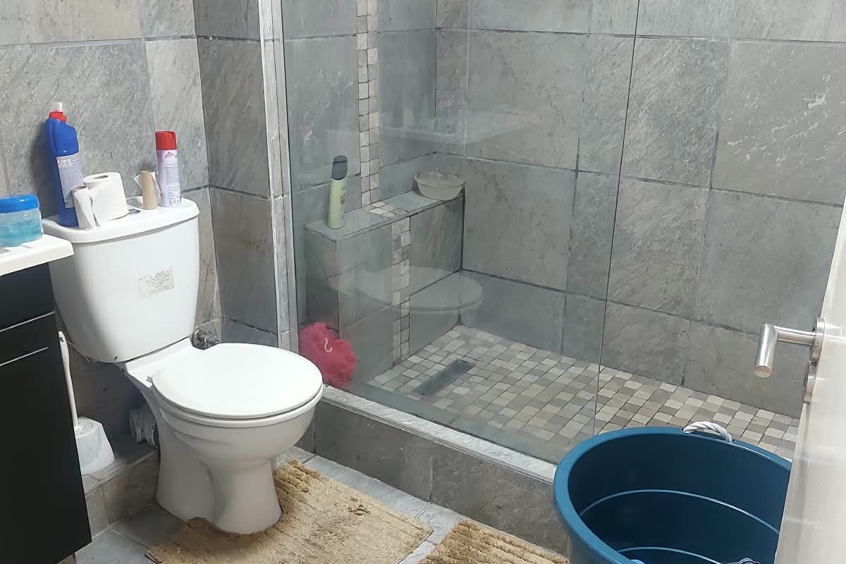 A functional bathroom featuring a walk-in shower with glass enclosure, tiled walls and flooring, and a vanity cabinet.